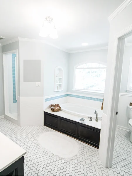 Completed elegant bathroom featuring a built-in bathtub, white hexagonal floor tiles, dark wood cabinetry, and modern fixtures by a Bathroom Renovation Company in Dubai.