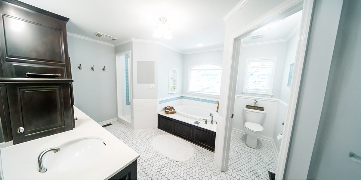 Completed elegant bathroom featuring a built-in bathtub, white hexagonal floor tiles, dark wood cabinetry, and modern fixtures by a Bathroom Renovation Company in Dubai.