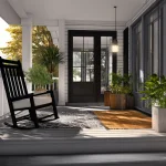 Modern renovated home front porch featuring a black rocking chair, potted plants, and sleek white siding designed by professional home renovation companies in UAE.